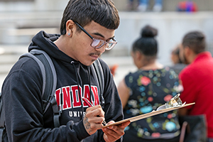A student writes on a clipboard.