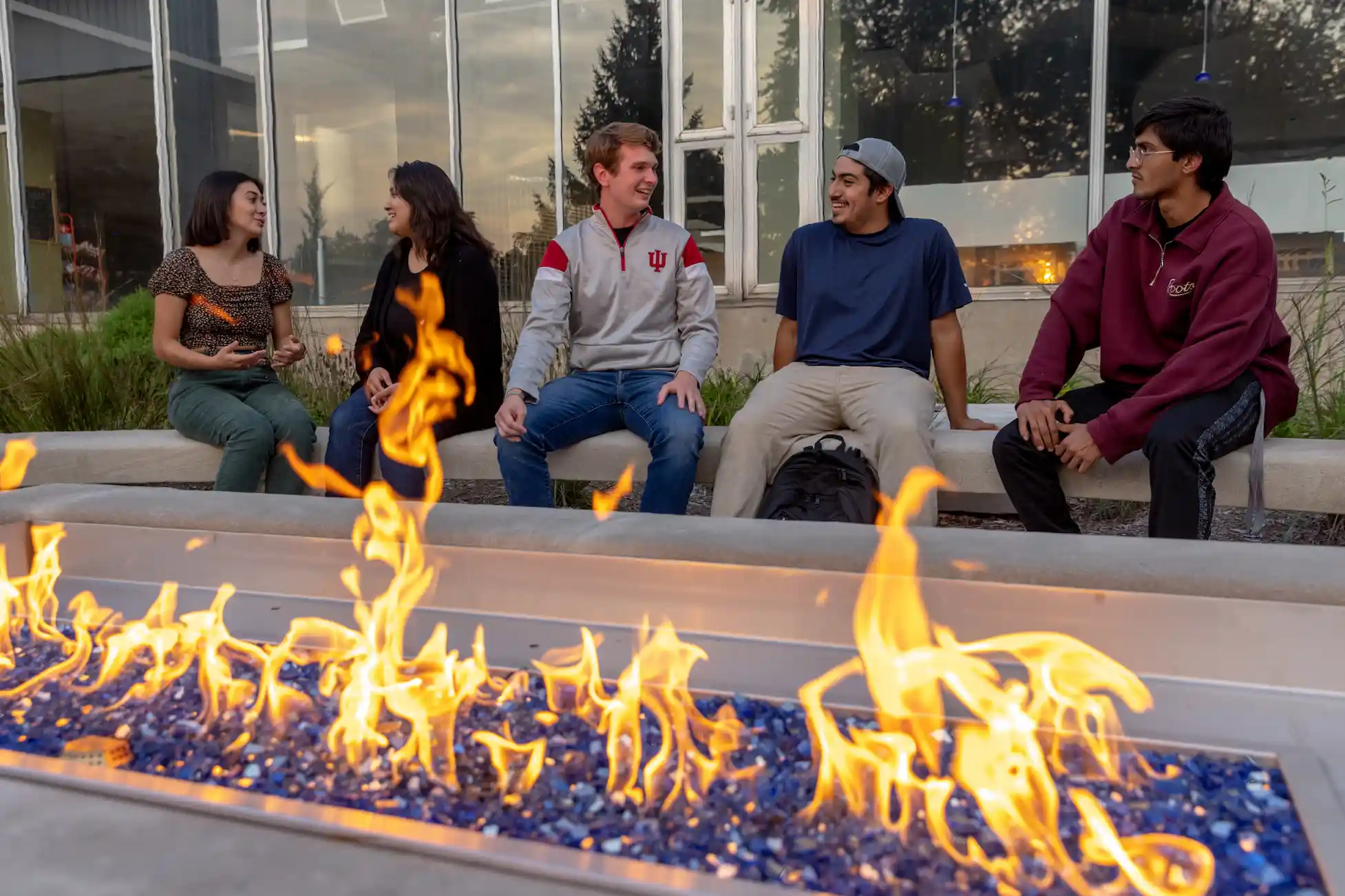 A group of college students sit around a campfire.