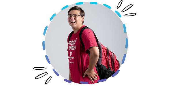 A male student wearing an IU Northwest shirt, laughing at the camera, in a circle frame