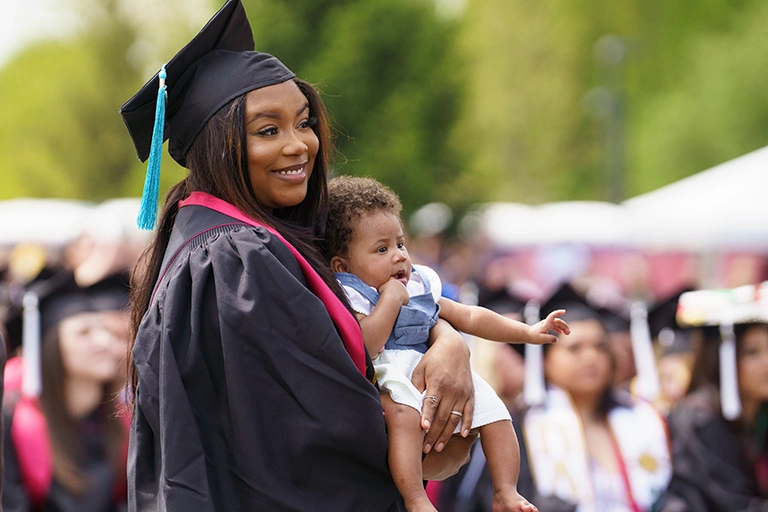 A women in a cap and gown holding a baby.