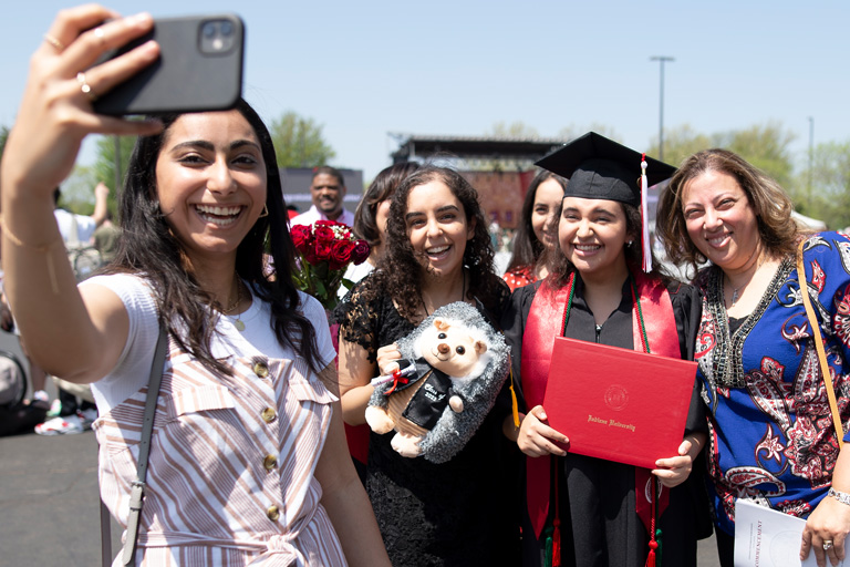 A stylish young woman takes a selfie with an IU Northwest graduate and family members