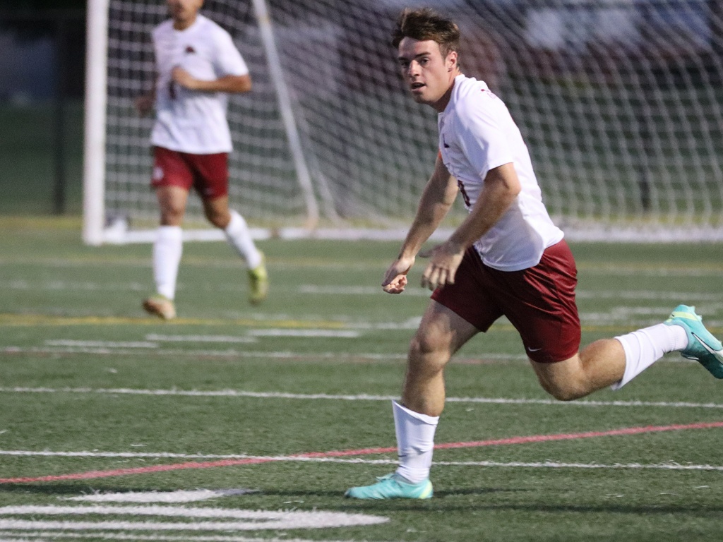 A men's soccer player runs on a field.