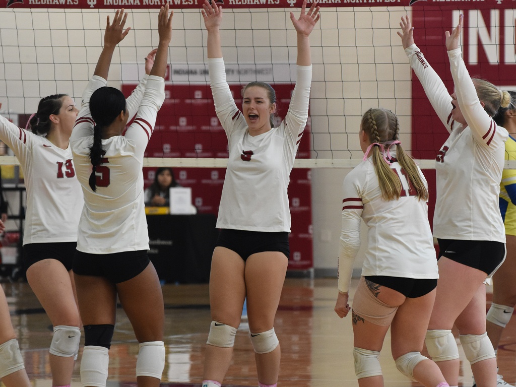 A women's volleyball team celebrates.